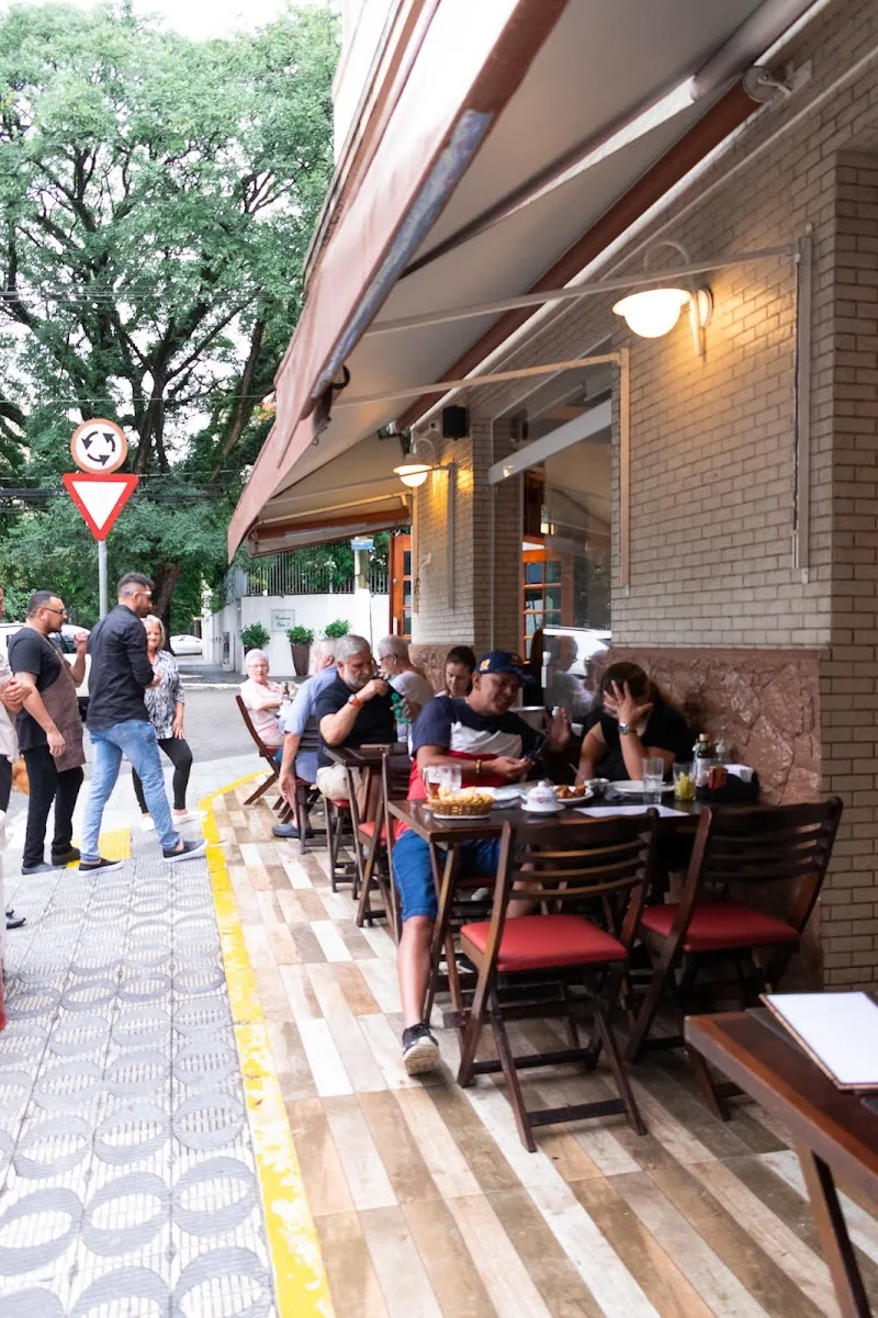 Mesas na calçada da Rua Fábia sob o toldo da casa, com clientes
